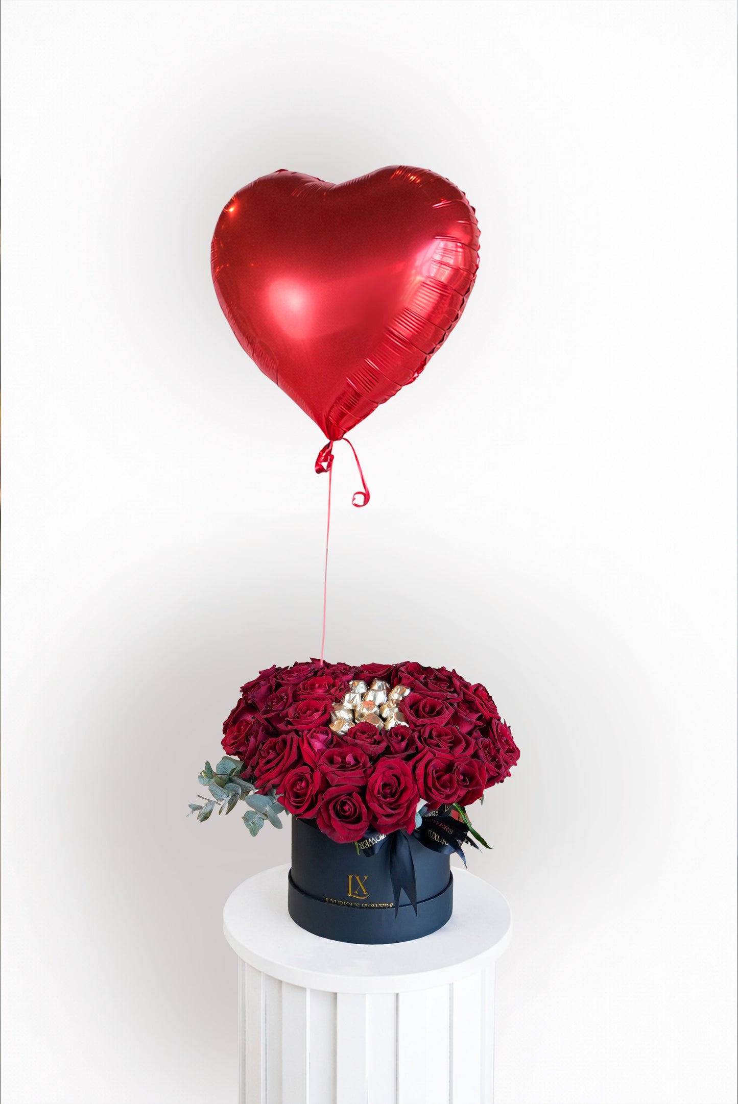 Luxury arrangement of fresh red roses with a plush teddy in a white ceramic pot for sale in Dubai