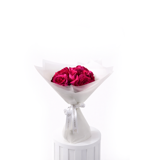Bouquet of 12 pink roses wrapped in white paper on a white pedestal with a white background for sale in Dubai online delivery
