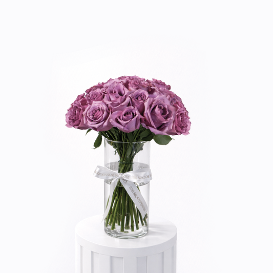 25 purple roses arranged in a clear glass vase