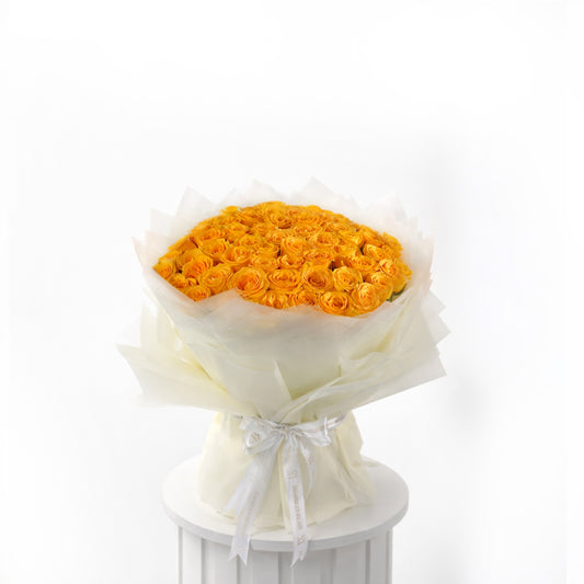Bouquet of 50 yellow roses wrapped in white paper on a white pedestal with a white background for sale in dubai