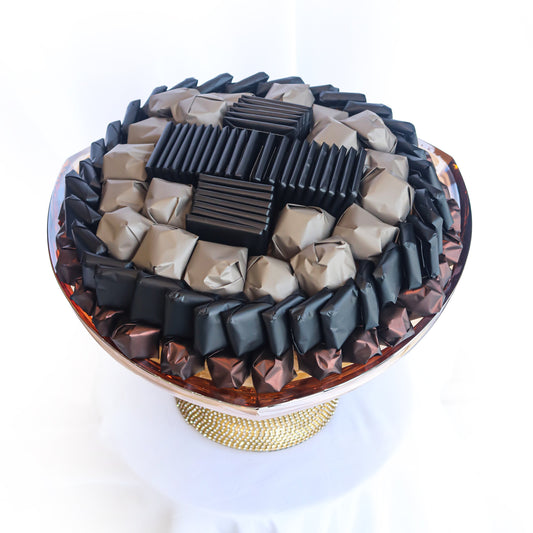 Assorted chocolate pieces on a decorative stand with a white background