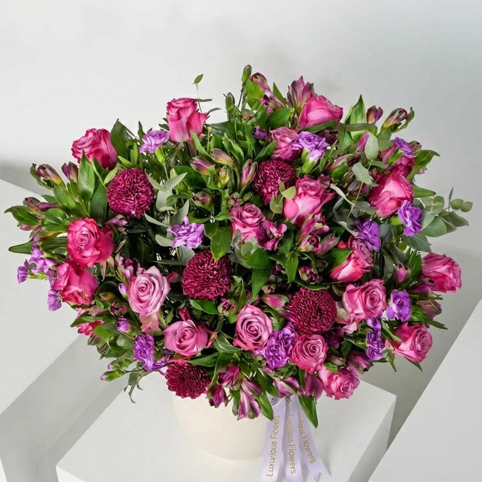 Bouquet of pink, purple, and green flowers on a white surface