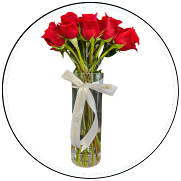 Bouquet of red roses in a clear vase with a white ribbon on a white background