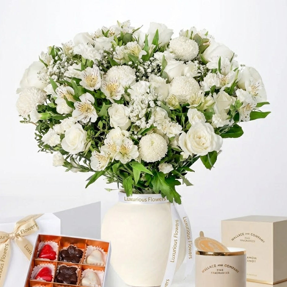 Bouquet of white flowers in a box with a box of chocolates and a candle on a white background