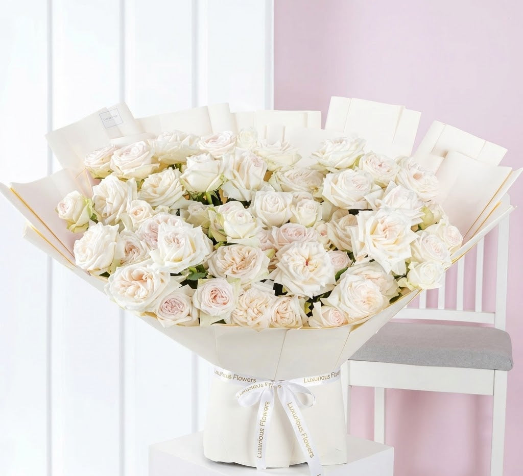 Bouquet of white flowers wrapped in paper on a white chair with a pink background