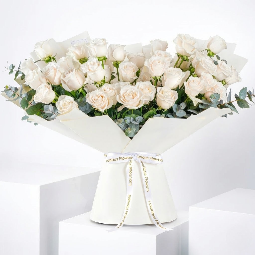 Bouquet of white roses with greenery in a white wrap on a white background