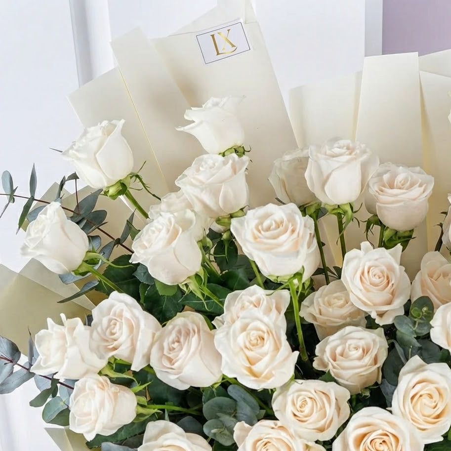 Bouquet of white roses with greenery on a light background
