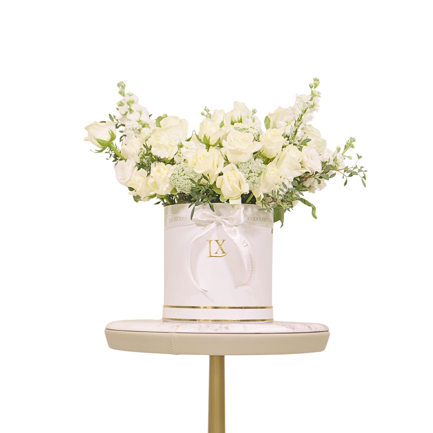 White flowers in a decorative box with 'LX' logo on a small table against a white background