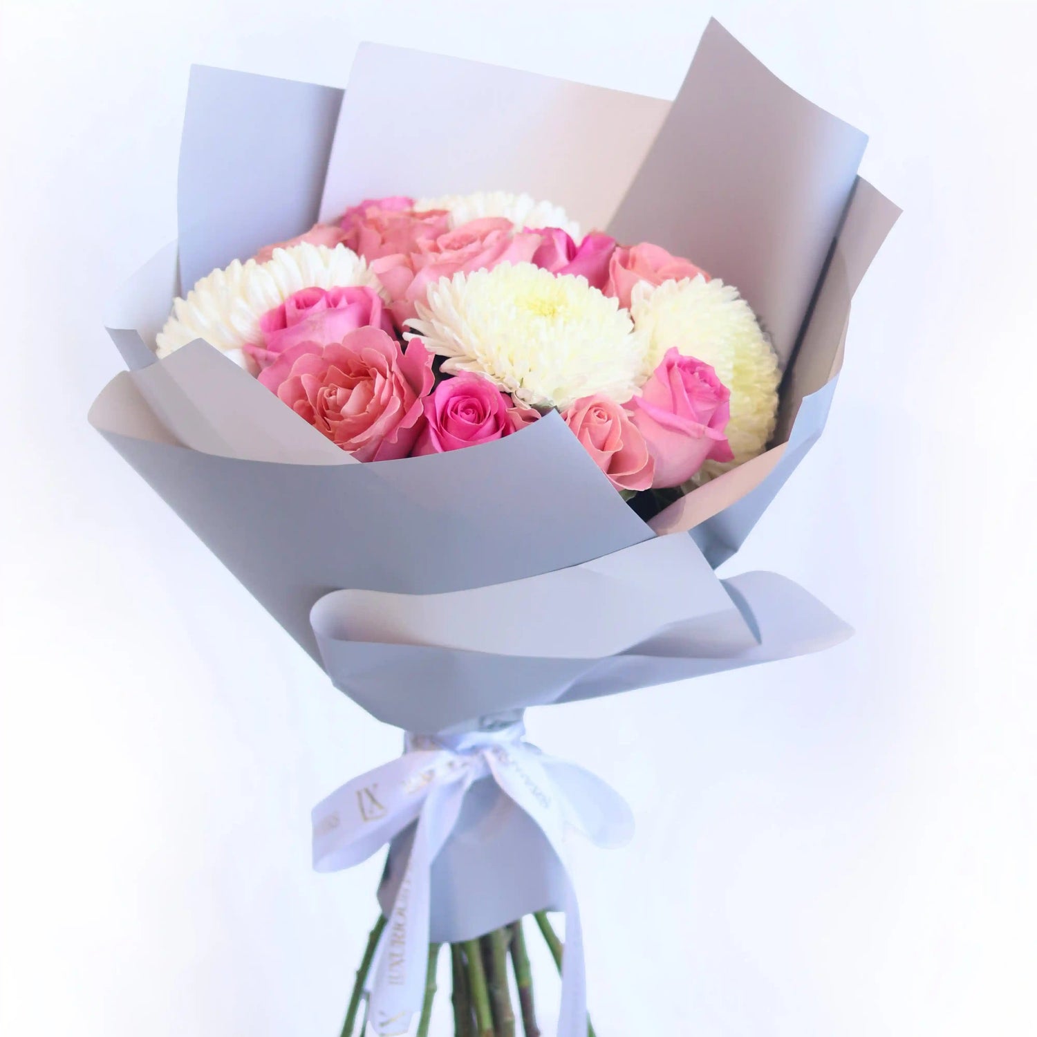 Bouquet of pink and white flowers wrapped in gray paper with a white ribbon on a light blue background