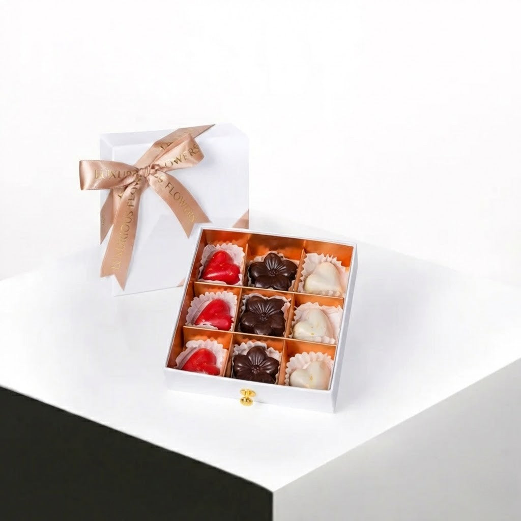 Open gift box with a ribbon containing assorted chocolates on a white surface.