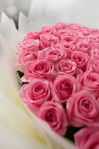 Large arrangement of 100 soft blush pink roses in premium white wrapping for sale in dubai