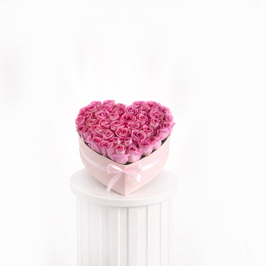 Heart-shaped bouquet of pink roses in heart a box on a white pedestal with a white background for sale in dubai