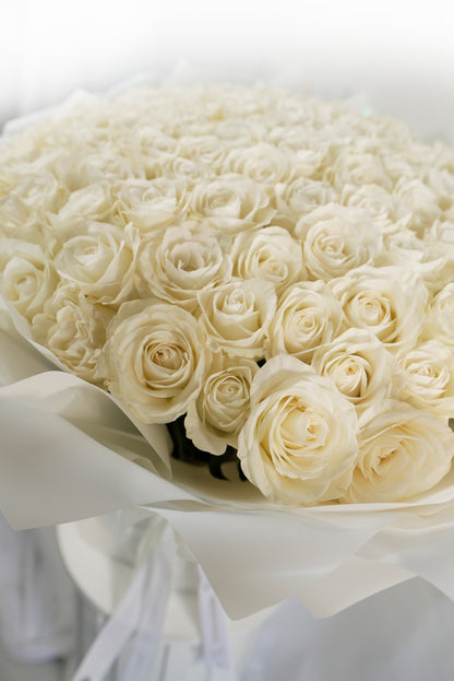Pristine 100-stem white rose arrangement in designer wrapping