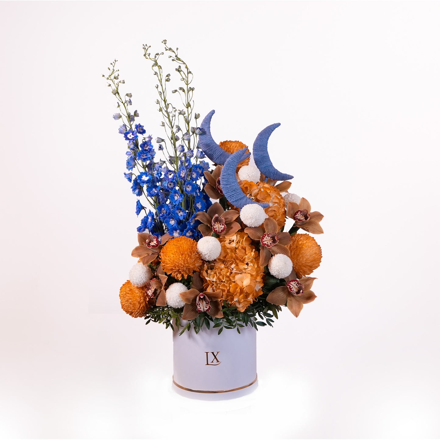 Luxury Ramadan flower arrangement in white box with crescent moon accents, blue delphiniums, orange hydrangea, and orchids in Dubai.