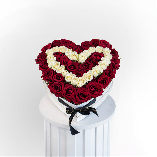 Red and white roses arranged in a heart-shaped luxury box for Valentine’s Day