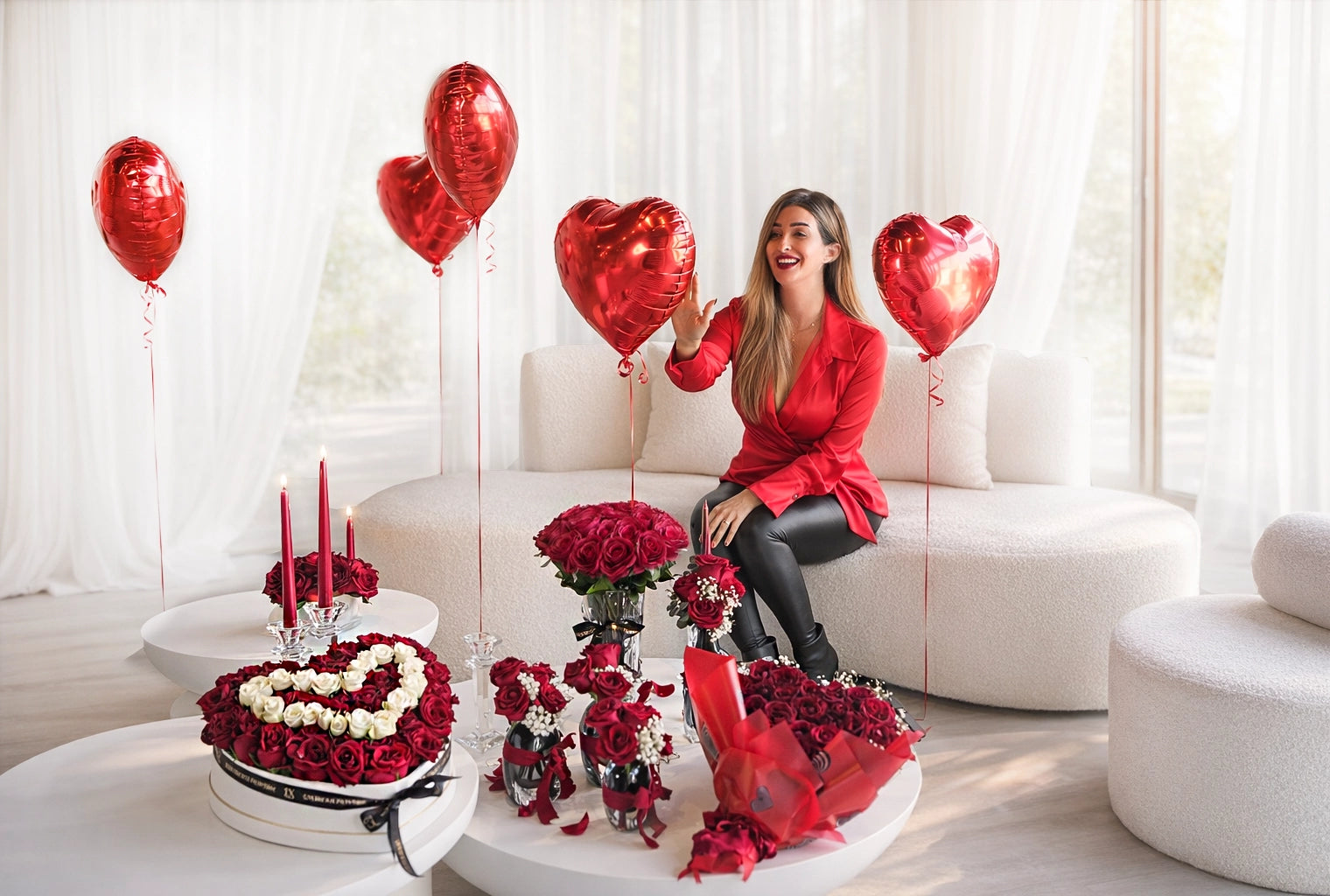 Woman in a red outfit sitting on a couch with heart-shaped balloons and floral arrangements in a decorated living room.