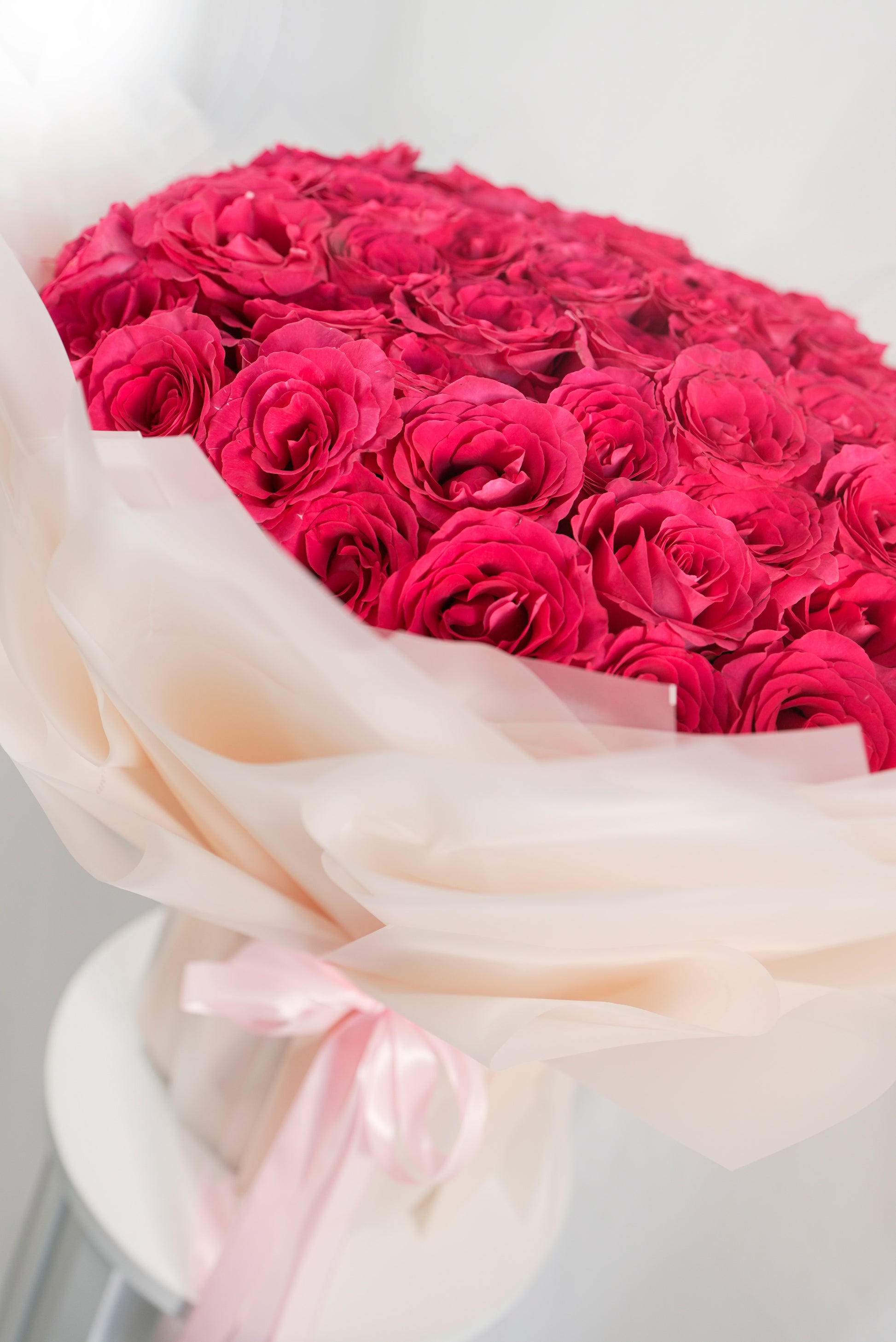 Detailed view of vibrant hot pink rose petals in a 100-stem arrangement for sale in Jumeirah 1 Dubai